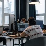 Equipe de desenvolvedores trabalha em computadores em um escritório moderno de tecnologia.