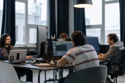 Equipe de desenvolvedores trabalha em computadores em um escritório moderno de tecnologia.