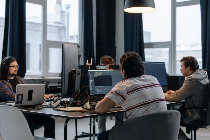 Equipe de desenvolvedores trabalha em computadores em um escritório moderno de tecnologia.