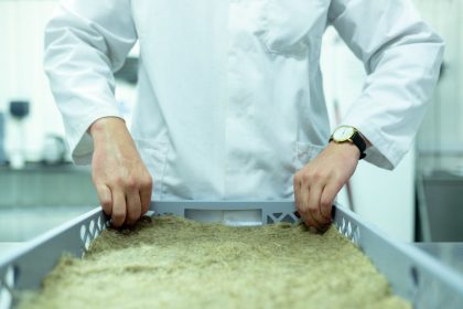 Cientista de jaleco manipula amostras em um laboratório voltado a pesquisas sustentáveis.