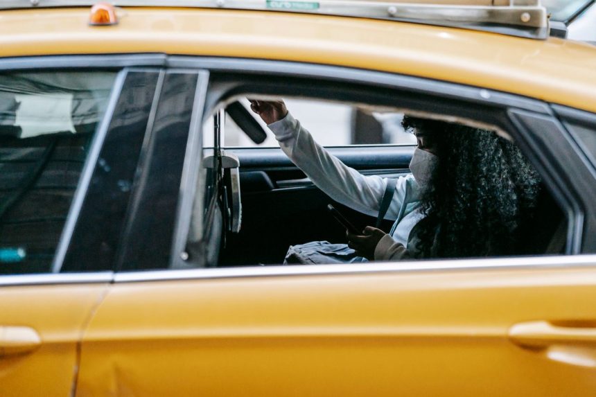 Passageira usa um smartphone sentada no banco traseiro de um táxi amarelo durante o trajeto pela cidade.