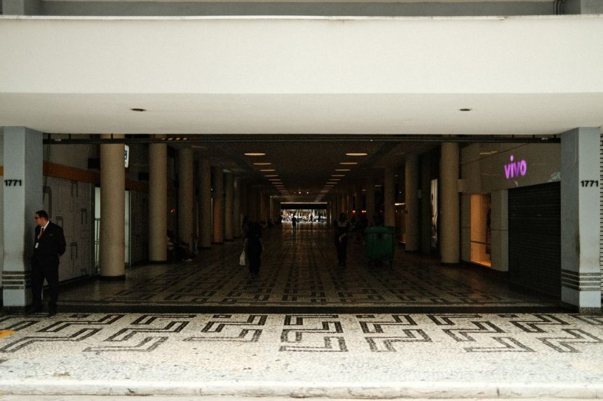 Corredor de um shopping center moderno, com lojas e pessoas circulando.