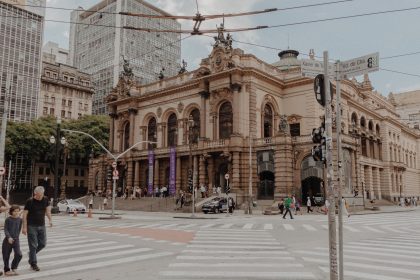 Vista do Theatro Municipal de São Paulo, cercado por arquitetura histórica e movimento de pessoas na área urbana.