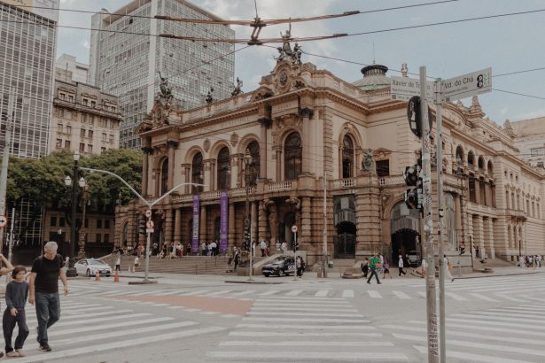 Vista do Theatro Municipal de São Paulo, cercado por arquitetura histórica e movimento de pessoas na área urbana.